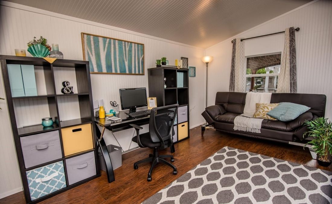 Finished backyard studio office with beadboard walls, desk, shelving and sofa
