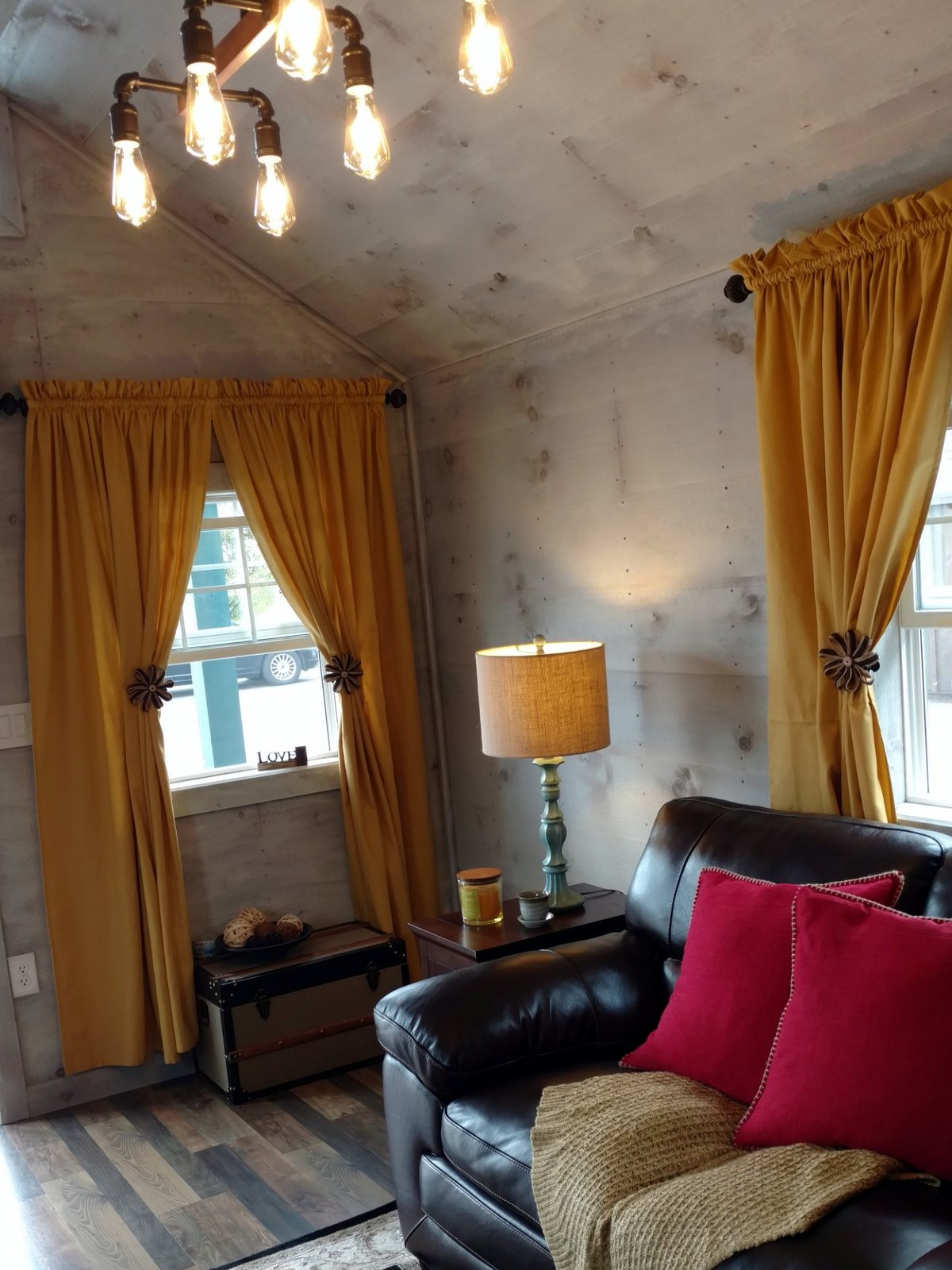 Rustic finished studio with pine plank walls, Edison light fixture, gold curtains and leather sofa